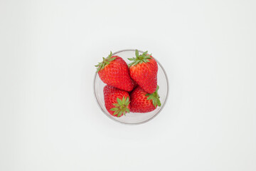 A space with a pure white background, lots of strawberries served in a glass bowl.