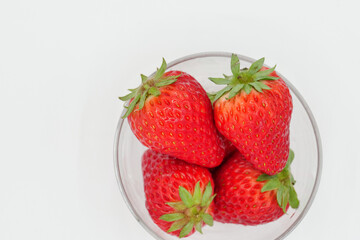 A space with a pure white background, lots of strawberries served in a glass bowl.