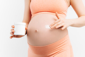 pregnant woman applying moisturizer to her belly on a white background
