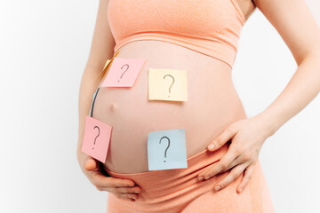 Close-up of a pregnant woman holding a paper with a question mark wondering about the gender of the...