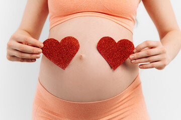 pregnant woman holds a symbol in the shape of a heart in her palms on a white background