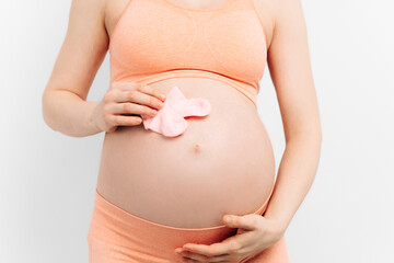 pregnant woman with baby socks on her belly. A pregnant woman holds her hands on her stomach