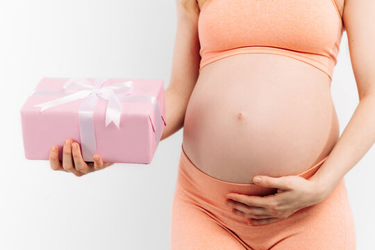 Cropped image of an attractive pregnant woman holding a gift box in her hands on a white background