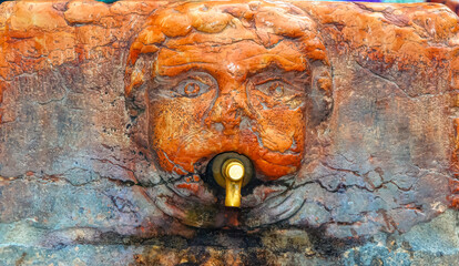 Old public fountain in shape of human head in downtown Verona, Italy.