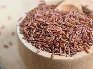 Red rice (brown rice) in a wooden bowl, red rice scattered on the ground.close up