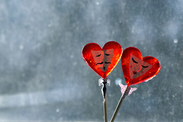 two heart-shaped lollipops with painted male and female faces