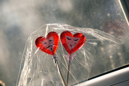 two heart-shaped lollipops with painted male and female faces