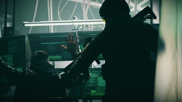 Tactical team with weapons and flashlights arresting cyber criminal using computers to hack database on dark base