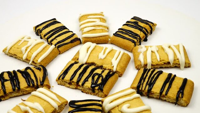 Shortbread cookies decorated with white and black chocolate icing are on a revolving cake stand