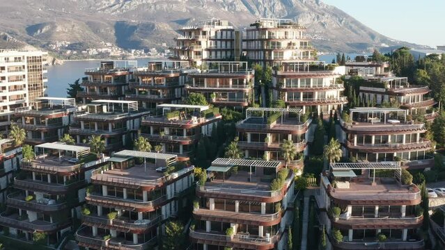 Luxury apartment buildings on the hillside - homes with view. Residences in a vacation tourist destination on the Mediterranean sea coast. Rooftops of green eco houses - aerial drone view on sunny day