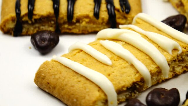Shortbread cookies decorated with white and black chocolate icing, pieces of chocolate are on a white photography turntable
