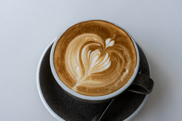 Hot latte With art milk froth in a coffee cup on a white table.