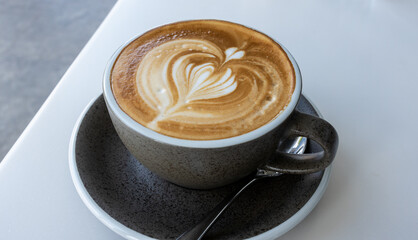 Hot latte With art milk froth in a coffee cup on a white table.