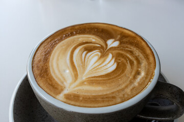 Hot latte With art milk froth in a coffee cup on a white table.