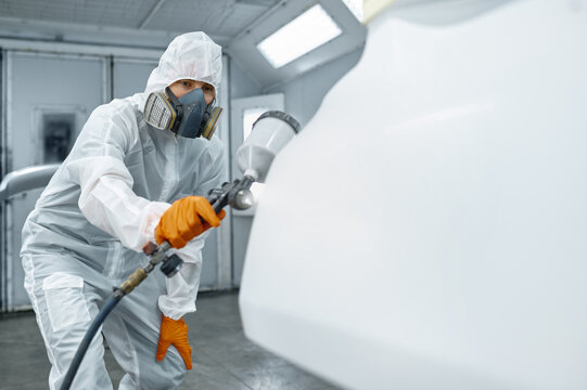 Technician in safety clothing spraying car paint