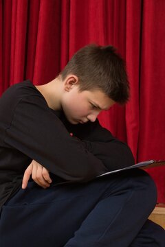 Backstage at the stage, a young actor is carefully studying his script