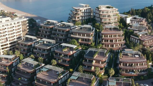 Luxury apartment buildings on the hillside - homes with view. Residences in a vacation tourist destination on the Mediterranean sea coast. Rooftops of green eco houses - aerial drone view on sunny day