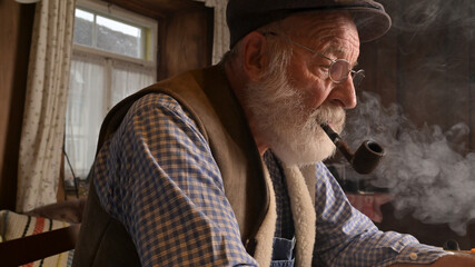Alter Mann Bauer mit Mütze raucht gemütlich Pfeife, erinnert sich an die Vergangenheit.