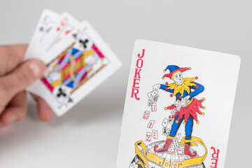 Jokerin hand on playing cards background