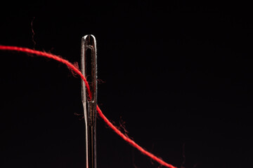 Red thread and needle on black background