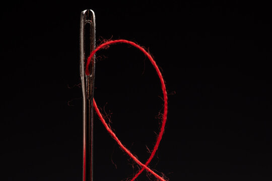 Red Thread And Needle On Black Background