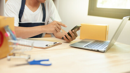 new generation entrepreneur Use smartphones and notebook computers to take customer orders and take notes. Order and prepare shipping packages online to order and prepare packaged products.