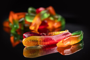 Fototapeta na wymiar Juicy colorful jelly worms sweets. Gummy candies. Snakes. On black backgriund