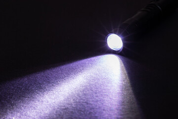 Flashlight and a beam of light in darkness. A modern led lamp with bright projection on dark table....