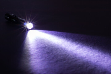 Flashlight and a beam of light in darkness. A modern led lamp with bright projection on dark table....