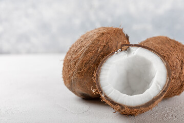 Ripe half cut coconut on light cement background. Composition with split coconut.Coconut cream and butter.Vegan food.Side view. Space for copy.