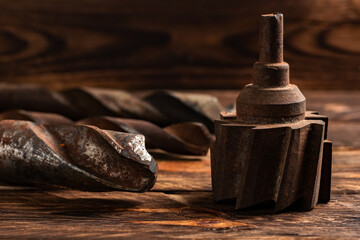 Set of metal drill bit of different sizes and cutter on wooden boards