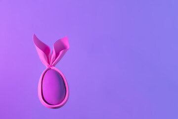 Foam pink egg with rabbit ears in neon holographic violet light. Creative handmade concept...
