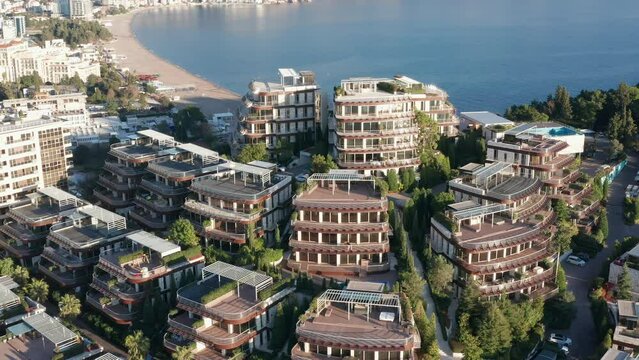 Luxury apartment buildings on the hillside - homes with view. Residences in a vacation tourist destination on the Mediterranean sea coast. Rooftops of green eco houses - aerial drone view on sunny day