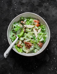 Delicious salad with baked turkey, apple, celery, green salad and Greek yogurt on a dark background, top view