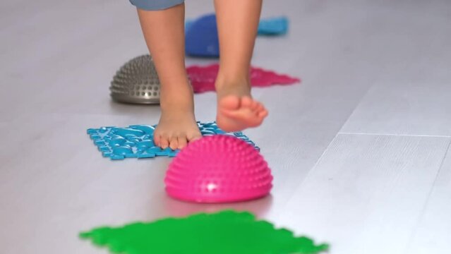 Flat feet physical therapy. child with a flat-bottomed stomach goes barefoot on an orthopedic foot mat for the appointment of an orthopedist. gymnastics for children.
