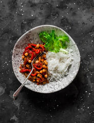 Vegetarian lunch - rice and eggplant, peppers, tomatoes sauce, chickpeas stew on a dark background, top view