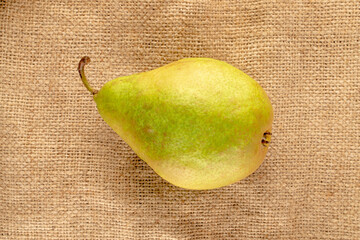 One sweet juicy pear on sackcloth , macro, top view.