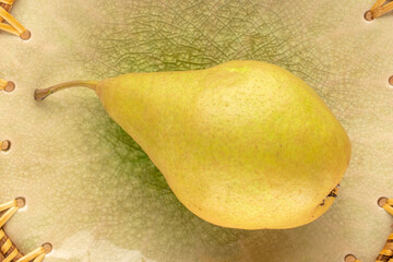 One sweet juicy pear on a ceramic dish , macro, top view.