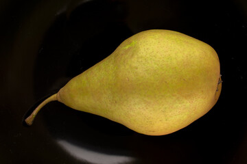 One sweet juicy pear on a ceramic dish , macro, top view.
