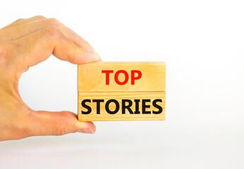 Top stories symbol. Concept words Top stories on wooden blocks on a beautiful white table white background. Businessman hand. Business story and top stories concept, copy space.