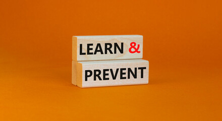 Learn and prevent symbol. Concept words Learn and prevent on wooden blocks on a beautiful orange table orange background. Business learning and learn and prevent concept, copy space.