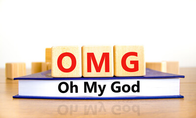 OMG oh my god symbol. Concept words OMG oh my god on wooden cubes on book on a beautiful wooden table, white background. Business and OMG oh my god concept. Copy space. - obrazy, fototapety, plakaty