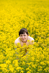 Fototapeta premium a beautiful girl in a pink T-shirt on the background of a floral yellow field