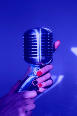 Vintage microphone in hands of a woman; blue or Very Peri color palette