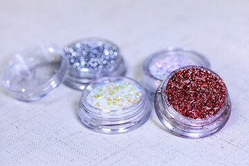 Beautiful multi-colored glitter and patal in a jar in a nail salon to create a nail design. Materials for manicure and makeup. 