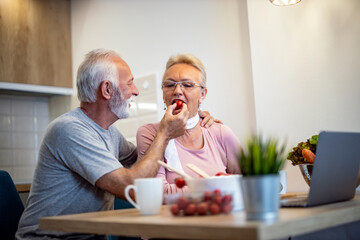 Senior couple at home preparing salads