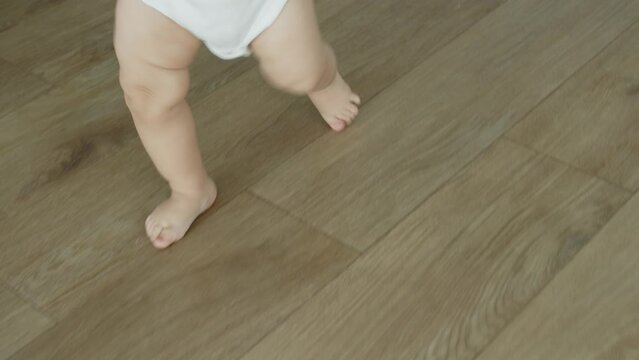 Close-Up Little Feet Walking On Warm Floor At Home, Baby Learning To Walk, Baby first steps Without Any Help. Toddler Exploring Home, Concept Newborn And Childhood, Slow Motion