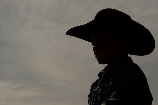 silhouette of a young boy wearing a cowboy hat