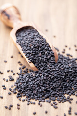 Bio natural black sesame seeds on wooden spoon.