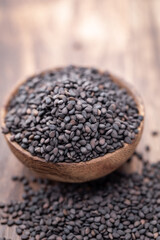 Bio natural black sesame seeds on wooden bowl.